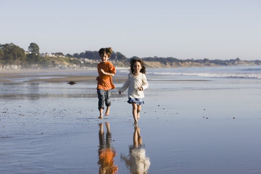 Two Little Kids Running Along the Water at The Beach