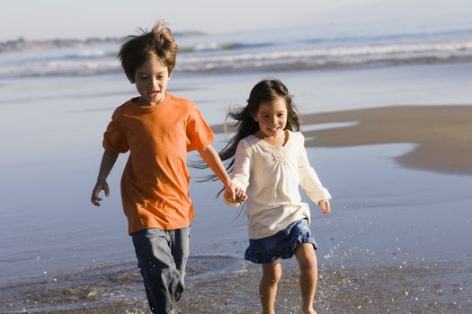 Two Little Kids Running Along the Water at The Beach