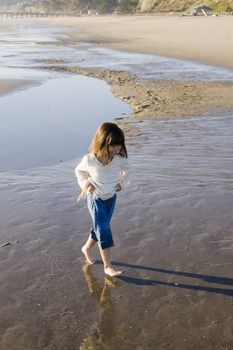 Little Girl Walking On The Edge Of Water At The Beach Hiking Up Pants