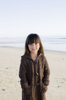 Portrait of a Little Girl Standing on The Beach Smiling To Camera