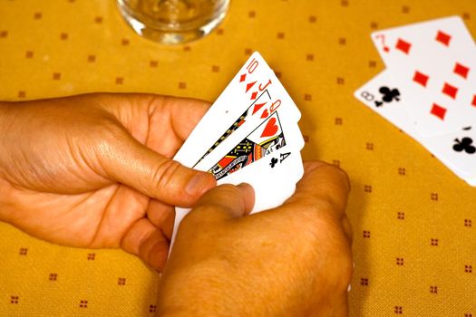 Hands of the player with playing cards on a game table