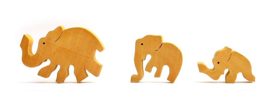 Three wooden toy elephants marching in a row. Isolated on white