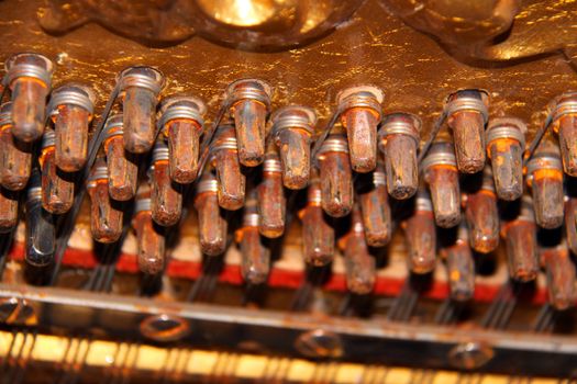 Inside an upright piano - tuning knobs and strings