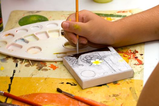 Hands of the young artist of the miniature painter drawing a picture.Work of the artist.