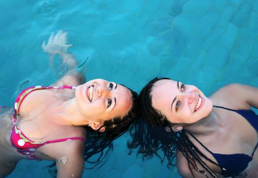 Two beautiful woman enjoying summer in the pool