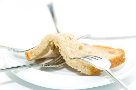 Some forks, white plateau and bread slice on a white background.  The concept of limitation of resources.
The concept  sharing between consumers.

