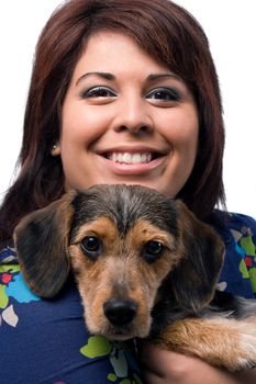 A young woman holding a cute mixed breed puppy isolated on a white background. The dog is half beagle and half yorkshire terrier.