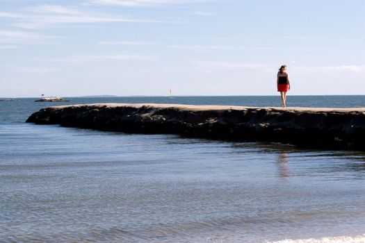 A woman walks down the jetty at the beach.