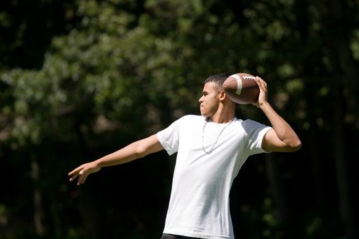 A young adult throwing a football outside.