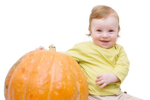 Smiling baby boy playing with pumpkin over white