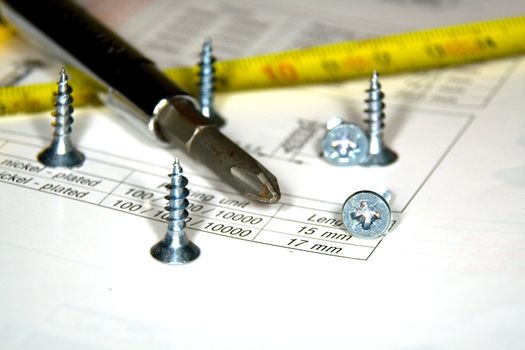 Screwdriver, screws and the drawing on a work desktop