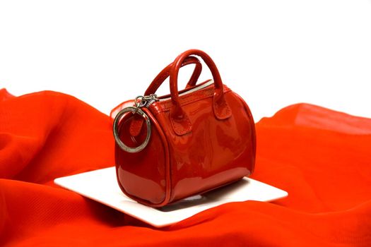Red elegant female handbag the beautician on a red fabric among white ware