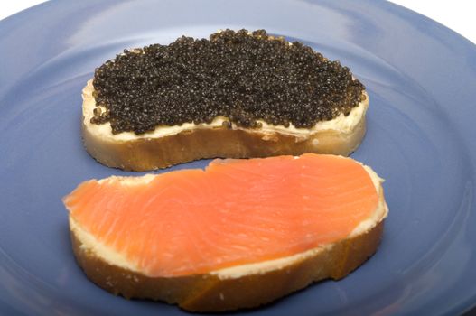 Sandwiches with red fish and black caviar on a blue plate.