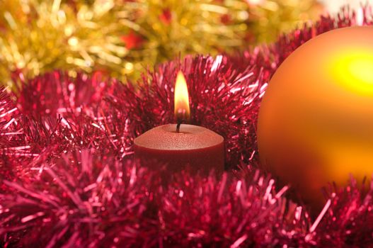 New Year's sphere a burning candle and a tinsel. Focus on a candle.