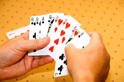 Hands of the player with playing cards on a game table