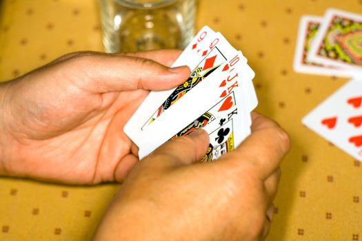 Hands of the player with playing cards on a game table