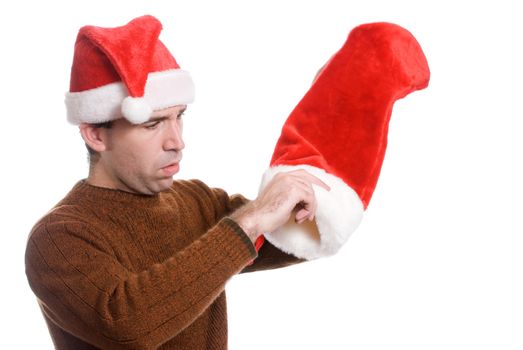 A young man wearing a Santa hat is dumping out his Xmas sock, isolated against a white background