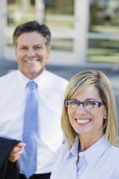 Businesswoman and Businessman Standing Outdoors Smiling To Camera