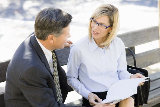 Portrait of a Businesswoman and a Businessman Sitting on a Bench Outdoors