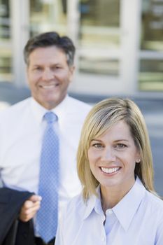 Businesswoman and Businessman Standing Outdoors Smiling To Camera