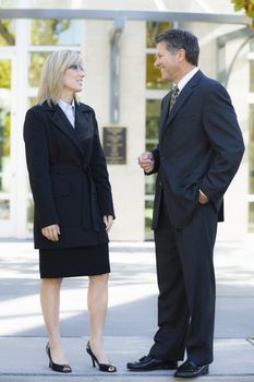 Businesswoman and Businessman Standing Outdoors Looking at Each Other