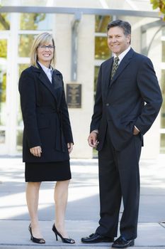 Businesswoman and Businessman Standing Outdoors Smiling To Camera