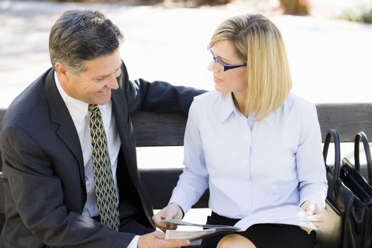 Portrait of a Businesswoman and a Businessman Sitting on a Bench Outdoors