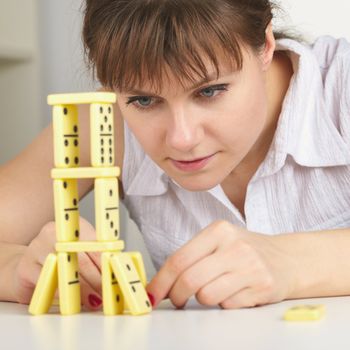 The young woman accurately builds a tower of dominoes
