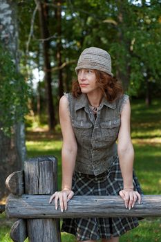 Red-haired women with cap in meadow near the wood and sea