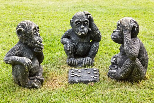 Three monkeys playing checkers sit on the lawn