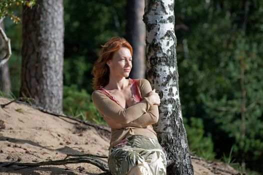 Red-haired adult women in dune looking at the sea