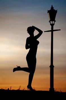 Silhouette of women dancing at sunset by lantern