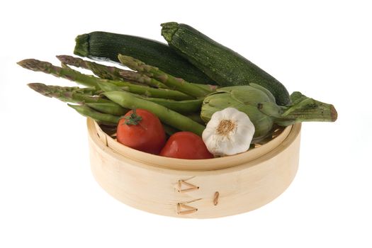 Bamboo steamer with tomatoes, asparagus, courgettes, bean pods and a head of garlic.