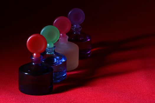 Colour bottles of the small size for cosmetics storage on a red background.