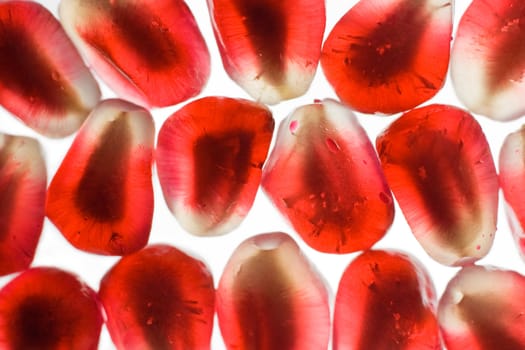 Bright translucent juicy pomegranate grain, arranged in linear order a solid background, close up, isolated on a white background