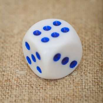 Grey plastic dice with blue dots on a canvas close up