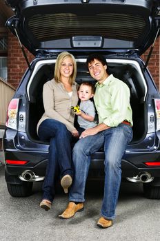 Happy young family sitting at back of car