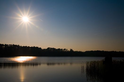 starry sun on the blue sky over the lake (Poland)