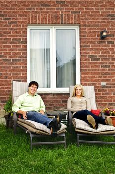 Happy couple in backyard of new home sitting on lounge chairs