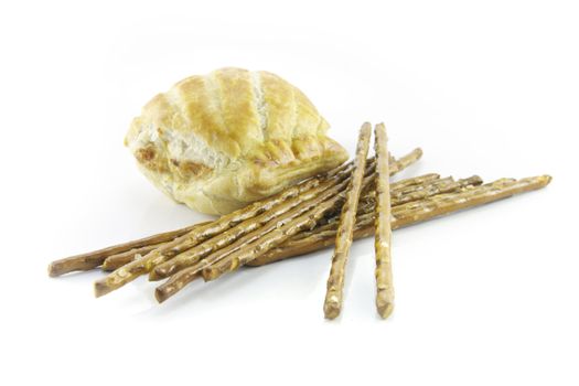 Small tasty sausage roll with salty pretzel  sticks on a reflective white background