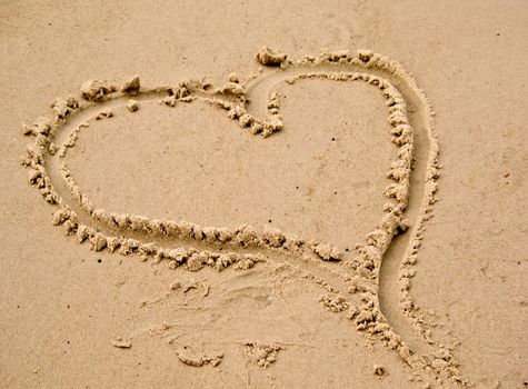 a love heart drawn in the sand at the beach