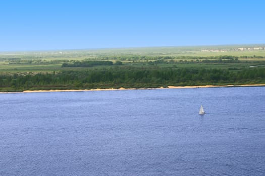 The yacht on a water smooth surface removed against a large forest