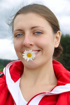 The girl on summer meadow with chamomile in teeth