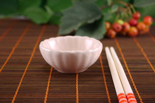 Cup and chopsticks on a wooden napkin against plants