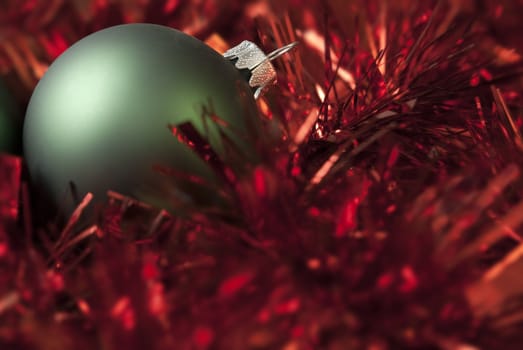 Green christmas ball on the red tinsel. aRGB.