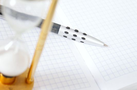 Sand-glass with the pencil and a notebook removed close up