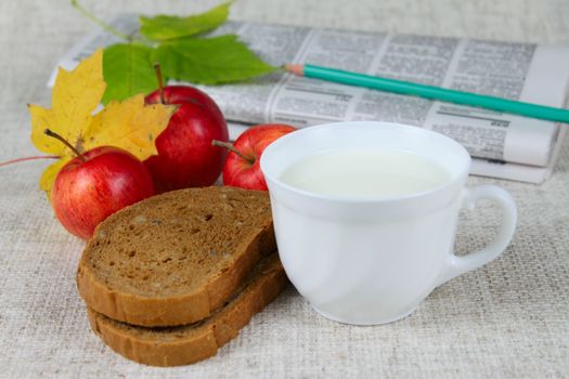 Bread with milk and apples against a morning paper removed close up