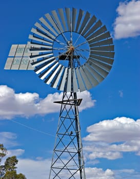 a big silver metal windmill in front of a nice cloudy blue sky