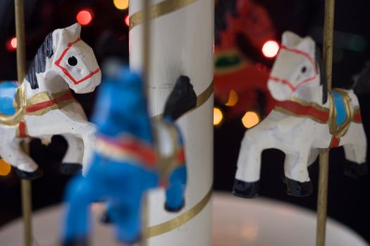 Miniature carousel with horses, against the background of New Year's lights. Depth of field for strong emotions.