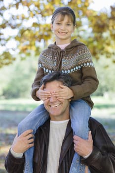 Portrait of a Father Holding Daughter on Shoulders in Park